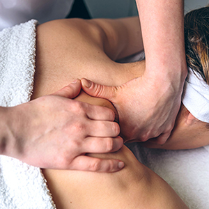 Close up of young woman receiving massage on shoulders in a clinical center. Medicine, healthcare and beauty concept.